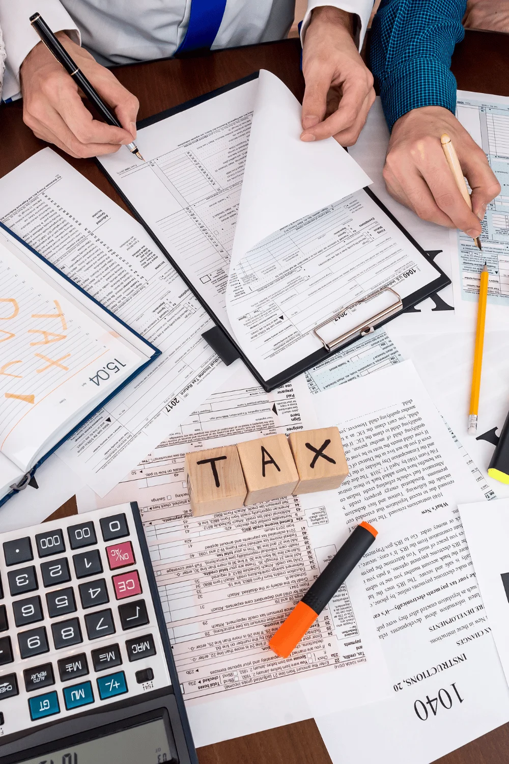 image of multiple people doing taxes with lots of paper on a table
