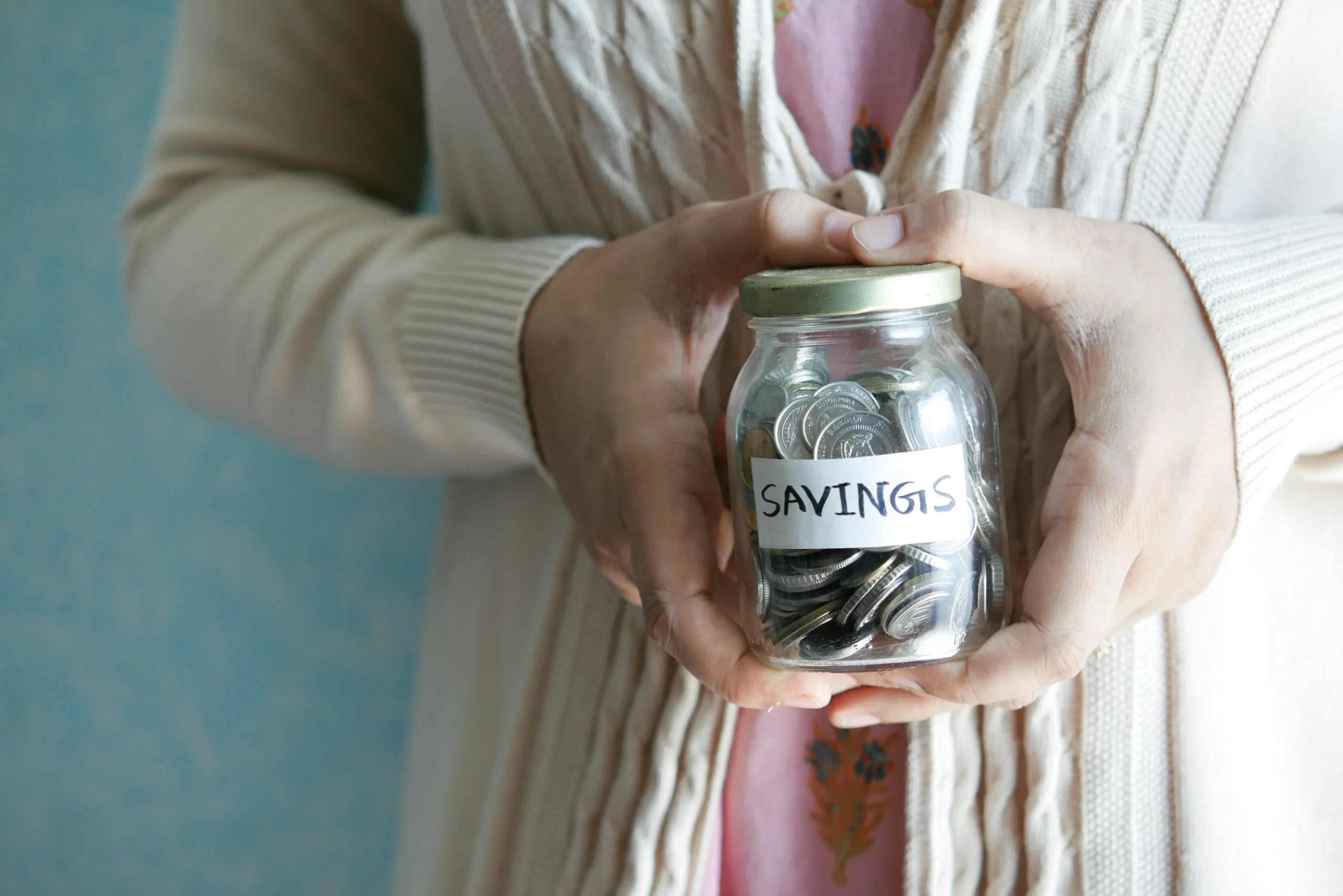 Someone is holding a jar of coins that says savings on it. They may benefit from having a budget bookkeeper.