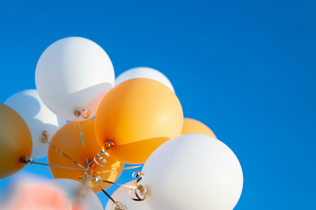 White and gold balloons fly together as they're strung to ribbons. They're being used to celebrate National Small Business Month at Simplicity Financial.