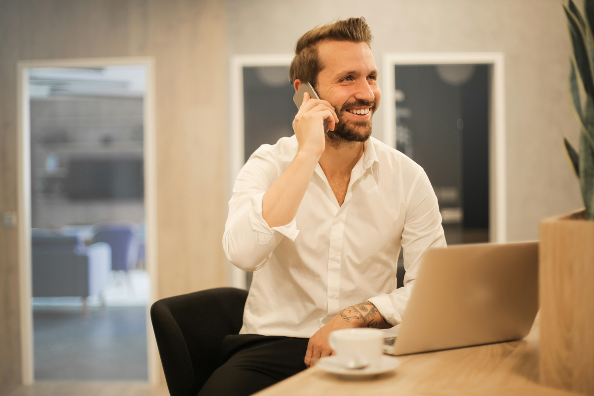 Someone is sitting at a desk in front of their laptop while they take a phone call on their cell phone. They're asking Simplicity Financial "Should I incorporate myself?"